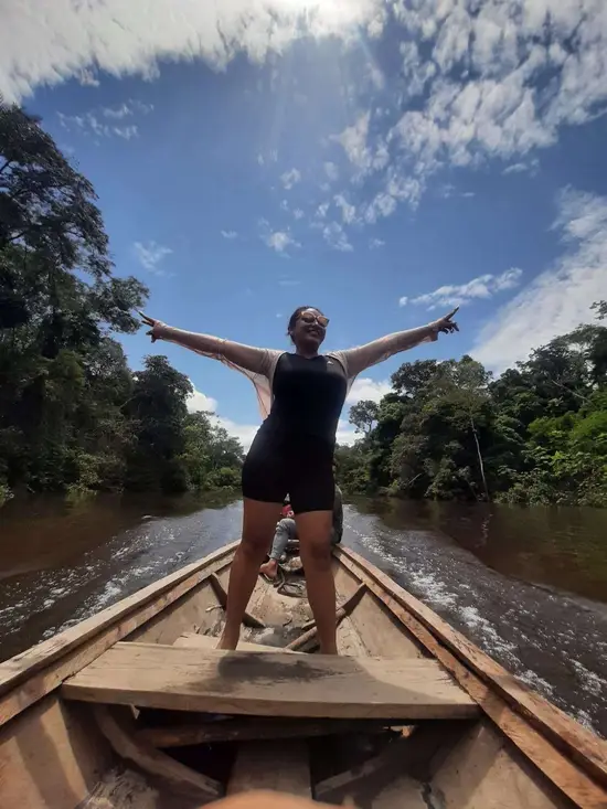 Traveler standing in a wooden boat on an Amazon river near Iquitos